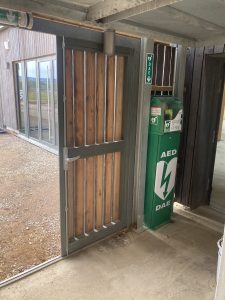Défibrillateur exterieur installé dans un boîtier mural sur un totem bornavie près d'une entrée